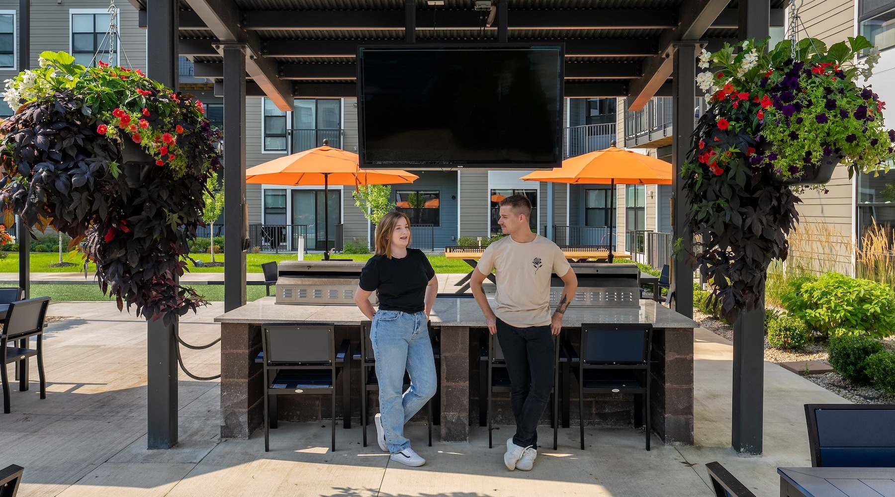 people talking in outdoors near a tv and covered grilling area